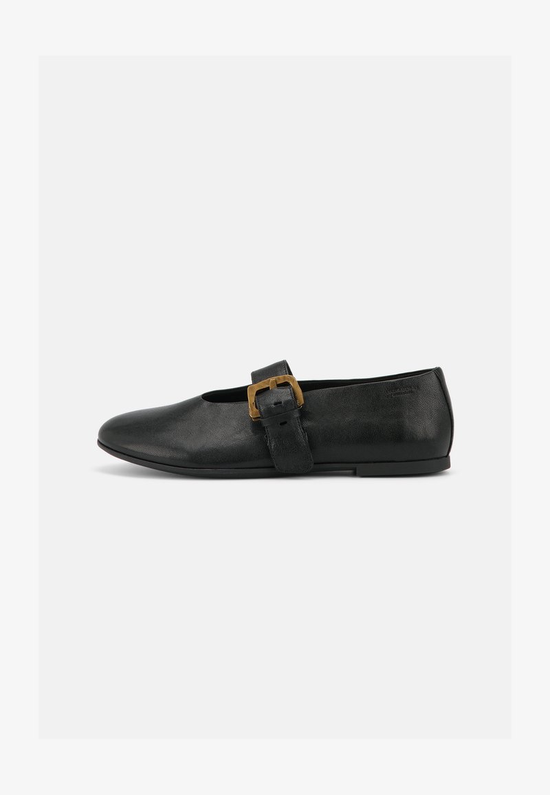 Chaussure plate en cuir noir avec une large bride et une grande boucle dorée sur un fond blanc uni.