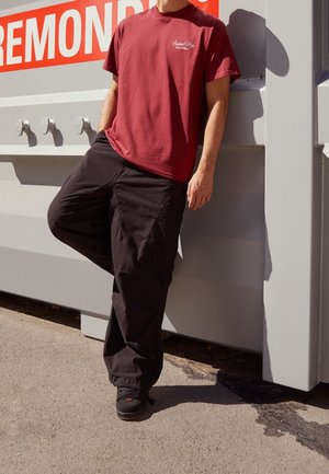 Bordowy bawełniany t-shirt, czarne spodnie bojówki i czarne buty. Casualowy strój o luźnym kroju; koszulka posiada mały detal z logo na piersi.