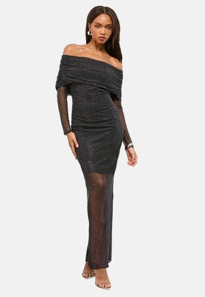 Čierne šaty bez ramienok s nariasením, priesvitnými dlhými rukávmi, bodkovanou textúrou a priliehavým strihom; po členky s jemným leskom.