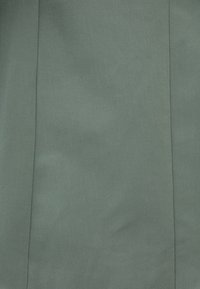 Tejido texturizado en verde apagado con superficie suave y sutil brillo. Presenta costuras rectas y un color uniforme en toda su superficie.
