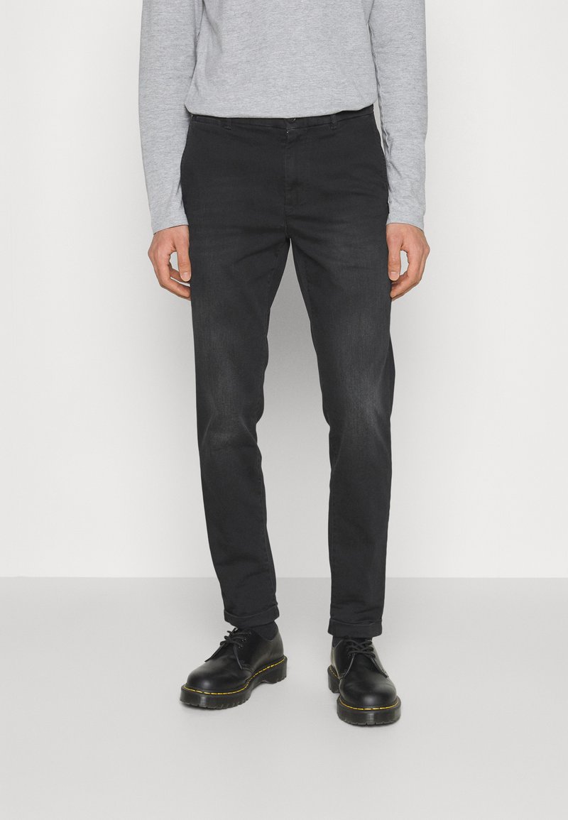 Schlichte schwarze Slim-Fit-Jeans aus Baumwoll-Denim mit klassischem Fünf-Taschen-Design und dezentem Verblassen, kombiniert mit schwarzen Lederschuhen.