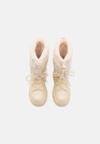 Crèmegekleurde schoenen met een pluche nepbont kraag, getextureerde zijkanten en vetersluiting aan de voorkant. Opvallend ronde hardware detail bij de kraag.