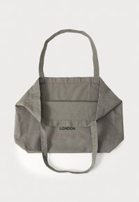 Borsa tote in cotone grigia con manici lunghi, caratterizzata da un design piegato e la scritta "LONDON" stampata sul davanti.