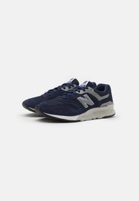 Navy blue athletic shoes with mesh and suede materials, featuring a grey logo, lace-up design, and cushioned white sole.