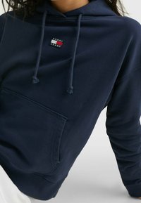 Felpa con cappuccio navy in morbido misto cotone, con tasca frontale e cappuccio regolabile con cordino. Piccola patch con logo sul petto.