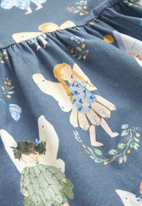 Tissu de robe avec des illustrations de filles en robe avec des ailes, entourées de petits motifs floraux et fruitiers sur un fond bleu.