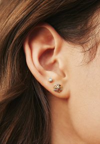 Guldörhängen med stift prydda med en samling flerfärgade stenar, inklusive bärnsten och klara kristaller, i en blommönsterdesign. Slät, polerad yta.