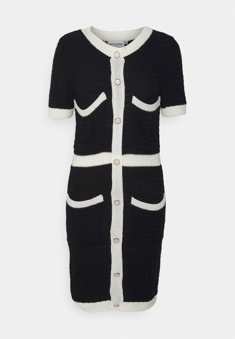 Robe en maille texturée noire avec bordure blanche, manches courtes, boutons sur le devant et quatre poches soulignées de blanc.