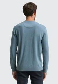 Helles blaues Strickpullover mit langen Ärmeln, runder Ausschnitt und gerippten Bündchen und Saum. Glatte Textur mit dezenten Nähten auf der Rückseite.