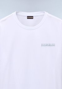 Camiseta de algodón blanca de manga corta con cuello redondo y un logo impreso en azul claro en el lado izquierdo del pecho. Textura suave, diseño casual.