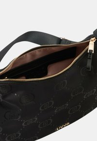 Borsa a spalla nera con finitura lucida, dotata di una cerniera dorata e tasche interne. Motivo logo testurizzato all'esterno, fodera interna liscia.