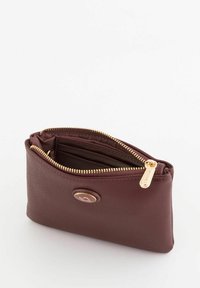 Mochila de cuero burdeos con un acabado texturizado, herrajes de cremallera dorados y un acento circular de marca en la parte frontal. El interior cuenta con compartimentos.