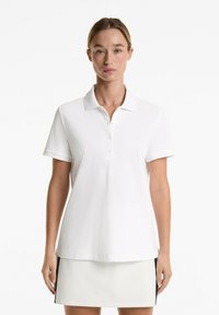 White polo shirt with a classic collar, three-button placket, short sleeves, and a straight hem. Made of soft, textured fabric.