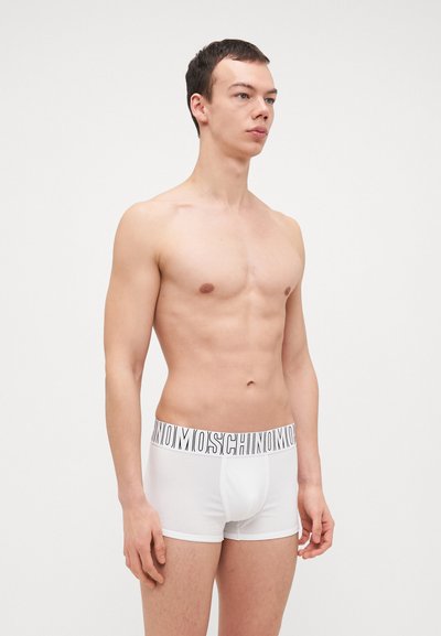 White boxer briefs with a black "Moschino" logo on the waistband. Cotton fabric, fitted design, mid-thigh length, smooth texture.