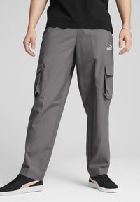 Gray cargo pants made of lightweight material, featuring side pockets and a logo on the thigh. Paired with black sneakers.