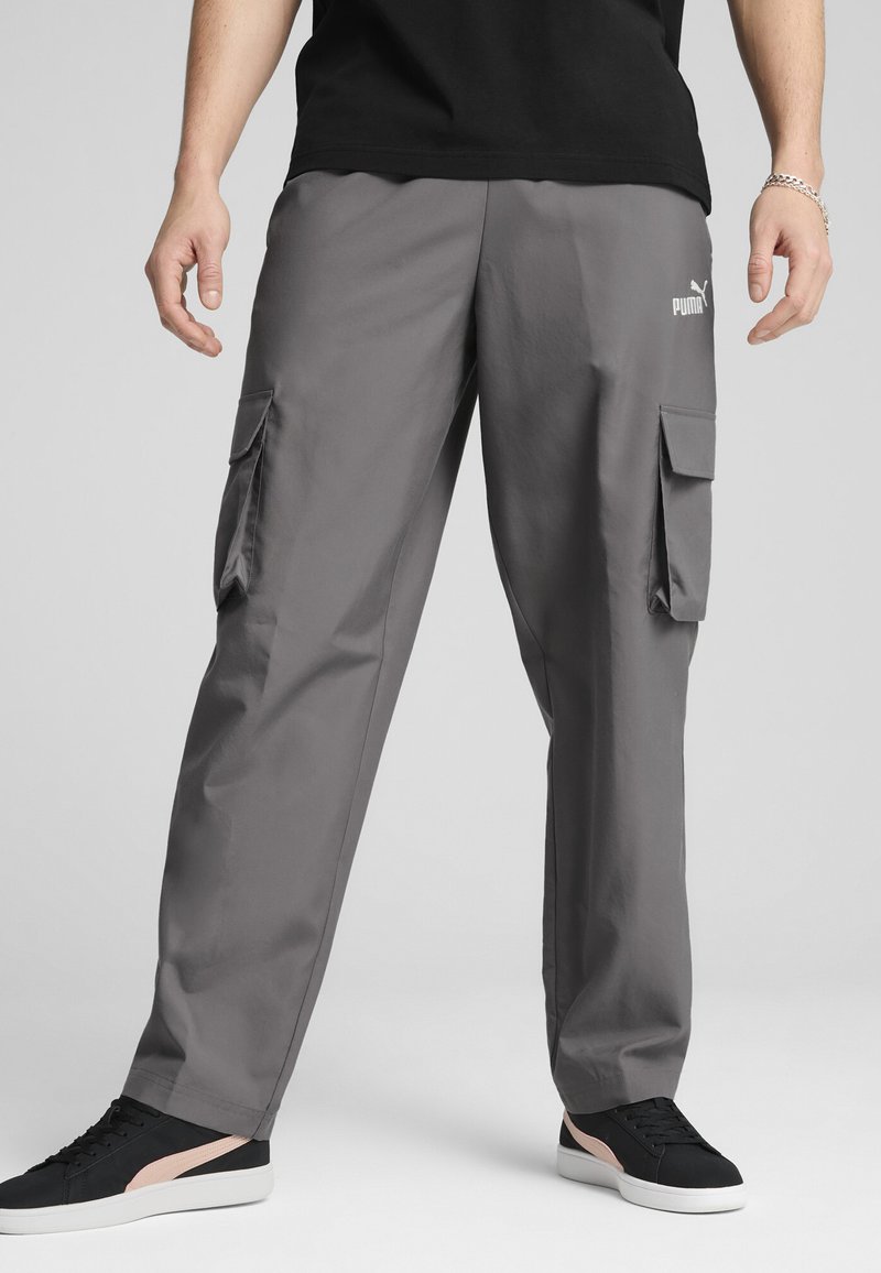 Gray cargo pants made of lightweight material, featuring side pockets and a logo on the thigh. Paired with black sneakers.