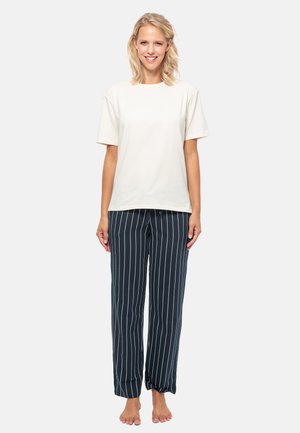 Beige bomull t-shirt med kort ärm, matchad med marinblå randiga pyjamasbyxor. Byxorna har vertikala vita ränder och en lös passform.