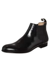 Botín Chelsea de cuero negro con detalles de brogue, paneles laterales elásticos, tirador en el tobillo y tacón bajo apilado.