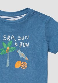 Blauwe t-shirt met korte mouwen, met geborduurde motieven van de zon, een palmboom, een papegaai en citrusvruchten, met de tekst "ZEE, ZON & VERMAAK." Zachte textuur.