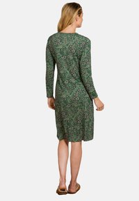 Langemouwen groene jurk met een bloemenpatroon, knielange snit, ronde halslijn en zachte stof. Gekocht met lichtbruine schoeisel.