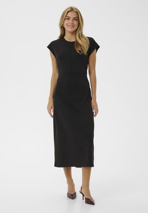 Black, knee-length dress with short, cap sleeves and fitted bodice. Smooth texture with a subtly defined waist. Paired with burgundy high heels.