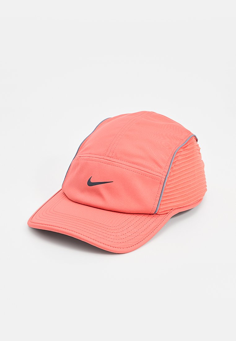 Casquette Nike rose corail avec logo swoosh noir, panneaux cousus et côtés à ribbes texturés sur fond blanc.