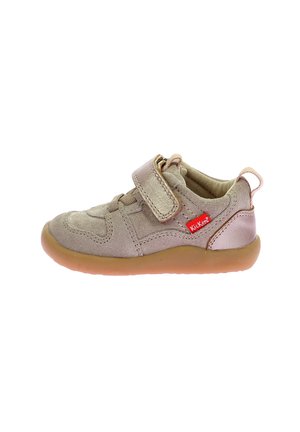 Chaussure beige pour enfants avec une sangle Velcro, tige en daim, semelle en caoutchouc, bout rond et un petit logo rouge. Texture lisse avec des détails de couture minimaux.