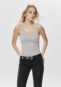 Gray tank top with a scoop neckline, made of soft fabric, paired with black distressed jeans and a silver belt. Simple design, casual wear.