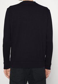 Svart bomullströja med rund halsringning, långa ärmar och ribbade mudd. Har en enkel design och avslappnad passform.