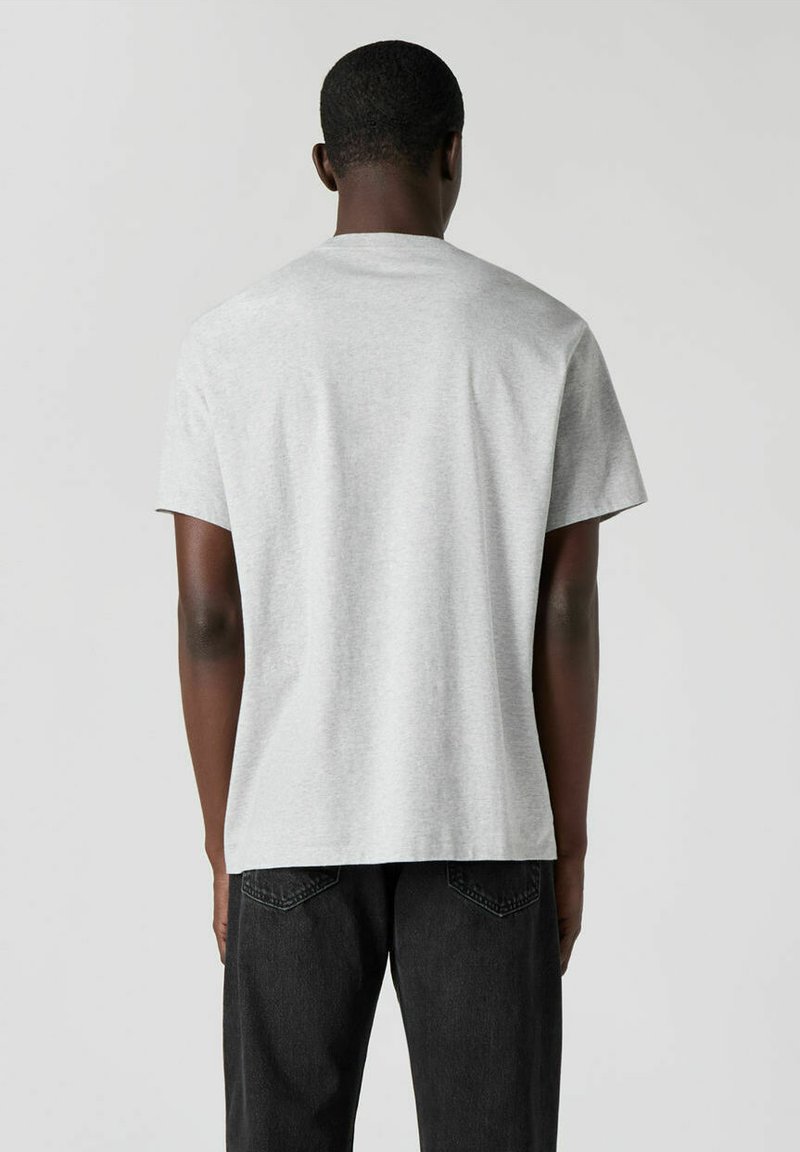 Graues Baumwoll-T-Shirt mit Rundhalsausschnitt und kurzen Ärmeln, das eine lockere Passform aufweist. Die Rückseite zeigt eine glatte Stofftextur und ein schlichtes Design.