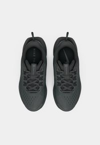 Baskets de sport noires avec une tige en mesh texturé, des lacets robustes et une semelle confort. Le design inclut un logo sur la semelle intérieure.