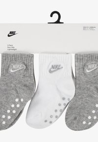 Három darabos csomag könnyű, csúszásmentes zokniból világosszürke, sötétszürke és fehér színekben, Nike logóval és tapadást biztosító gumis pöttyökkel.