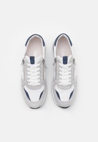 Sneakers med en kombination av vitt läder och grå mocka, blå accenter, en texturerad yta och en sidogylf för lätt åtkomst.