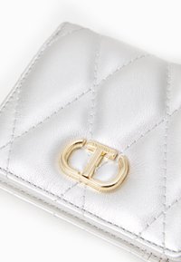 Silver quilted leather wallet featuring a gold-tone hardware closure with a prominent logo detail. Smooth texture with stitched accents.