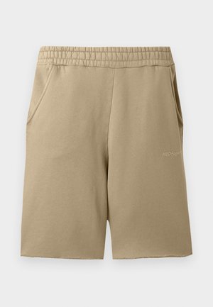 Beige Sportshorts aus weichem Stoff, mit einem elastischen Bund, zwei Seitentaschen und einem kleinen Logo am Saum.