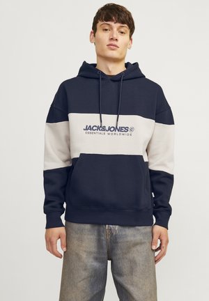 Sudadera a rayas en colores azul marino y beige, con bolsillo frontal, capucha con cordón y texto del logo en el pecho. Material mezcla de algodón.