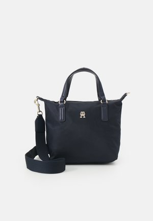 Zwarte totebag met korte handvatten, afneembare brede schouderriem en klein gouden logo aan de voorzijde in het midden.