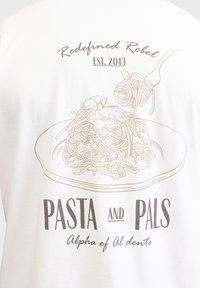 Hvid T-shirt med en stregtegning af spaghetti på en tallerken med teksten "Pasta and Pals" og "Redefined Rebel" ovenover i afdæmpede farver.