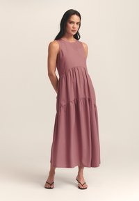 Bezsleeve mauve maxi kleita ar apaļu kakla izgriezumu, ar slāņainu dizainu un plūstošu siluetu. Izgatavota no viegla auduma ar gludu tekstūru.