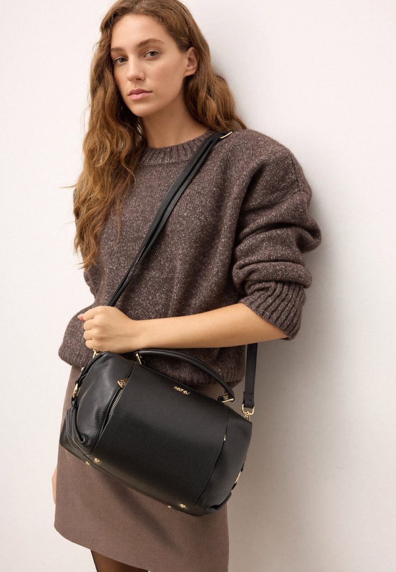 Melnas ādas somiņa ar strukturētu formu. Aprīkota ar augšējo rokturi, regulējamu siksnu, zelta krāsas detaļām un ar rāvējslēdzēju aizveramu kabatu.