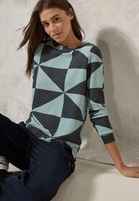Camicia azzurra a maniche lunghe con un motivo geometrico nero e azzurro, dotata di scollatura a barca e texture a coste.