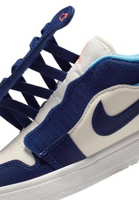 Granatowo-białe trampki z teksturowaną cholewką i sznurowaniem z tkaniny. Posiadają wzorzysty język i detal z logo po boku. Podeszwa z gumy.