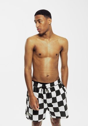 Schwarz-weiße karierte Badeshorts mit einem elastischen Bund, Kordelzug und einem Logo auf der unteren linken Seite.