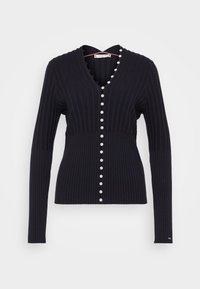Cardigan navy a coste con scollo a V, caratterizzato da bottoni simili a perle lungo la parte anteriore e maniche lunghe. Il tessuto ha un aspetto testurizzato.