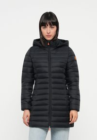 Zwarte pufferjas met een capuchon, gebiesde ontwerp, voorrits en elastische manchetten. Heeft oranje accenten op de rits en het sleeve-logo.