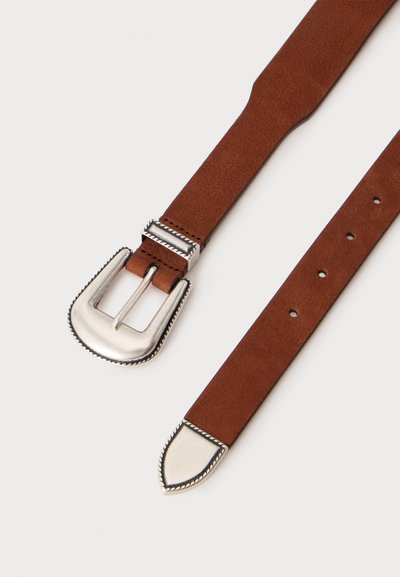 Ceinture en cuir marron avec boucle en métal argenté et extrémité, présentant des bords décoratifs rainurés et plusieurs trous d'ajustement sur un fond clair.