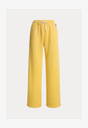 Rumene trenirke s širokimi hlačnicami, elastiko v pasu in vrvico za zavezovanje. Iz mehkega materiala s čistim zaključkom in brez vidnih vzorcev.