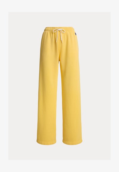 Gule joggebukser med vid ben, elastisk midje og snøring. Laget av mykt materiale med en ren finish og uten synlige mønstre.