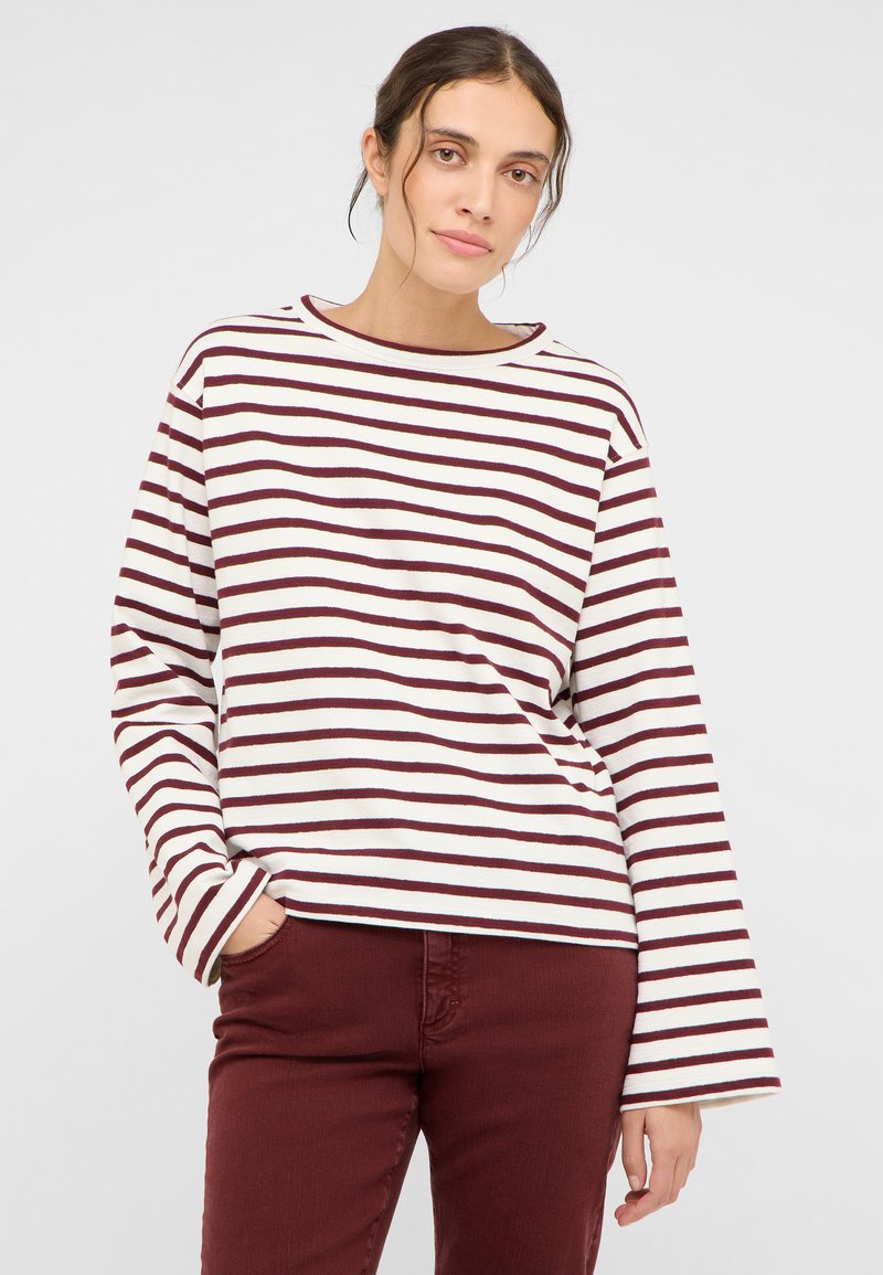 Gestreiftes langärmeliges Oberteil mit Bootsausschnitt, mit weißen und dunkelroten Streifen; weicher Baumwollstoff; lockere Passform, kombiniert mit dunkelroter Hose.