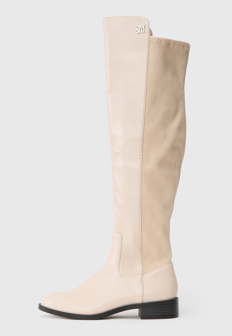 Beige over-the-knee støvler med en glat læderfor og en ruskindsbag, en rund tå og en lav blokhæle. Initialerne "SM" prægede øverst.